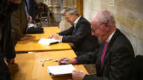 Harry Goodhew (front) and Stuart Piggin sign copies of the biography.